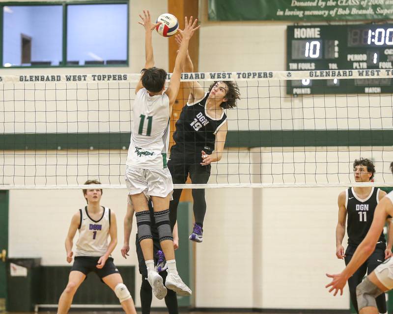 Downers Grove North's Zak Baker (19) with a kill attempt past the defense of Glenbard West's Brayden Tejeda (11) during volleyball match between Downers Grove North at Glenbard West.  April 2, 2024.