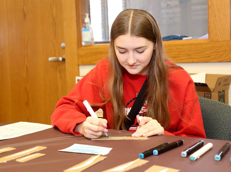 Abigail Plank colors one of the many waves for the “Sunset over the Fox River” Community Art Project at the Yorkville Public Library Mini Golf FUN Raiser on Sunday, Feb. 2, 2025 in Yorkville.