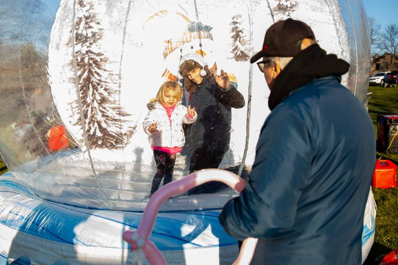 Lockport residents Sean and Ava Shepherd wave to Bill Shepherd while in the Giant Snow Globe at Christmas in the Square in Lockport on Saturday, Nov. 25, 2023.