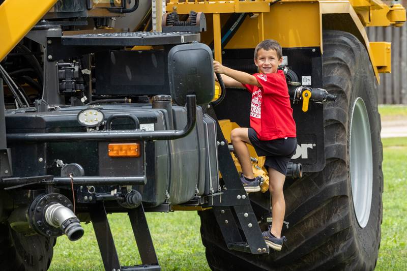 Daxton Blair climbs construction vehicle at the 21st annual Convoy Against Cancer on Saturday, July 19, 2025 on Main Avenue in Ladd.