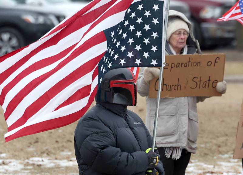 A protester hold an upside down flag Thursday, Feb. 5, 2026, in front of Genoa-Kingston High School. The group is protesting the “History Rocks” assembly which is part of a nationwide campaign by the U.S Department of Education tied to the nation’s 250th anniversary and organized by the high school’s Turning Point USA, Club America chapter, a nonprofit founded in 2012 by the late Charlie Kirk.