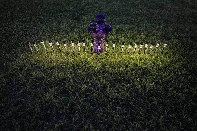 Lights illuminate a cross made of flowers at a memorial site in the town square for the victims killed in this week's elementary school shooting on Friday, May 27, 2022, in Uvalde, Texas. (AP Photo/Wong Maye-E)