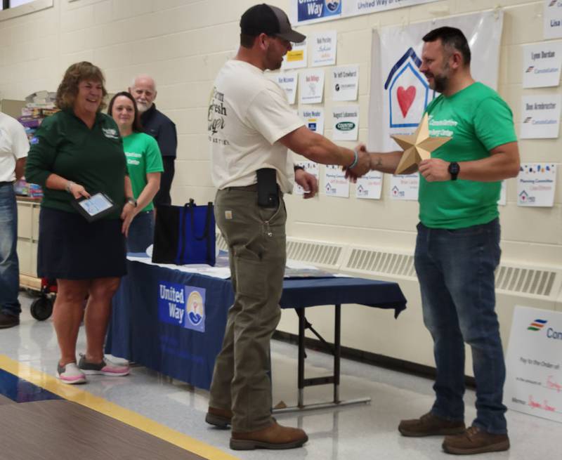 Longtime Labor of Love volunteer Joe Ward (right) receives a gold star prior to setting out on his final day as part of the local effort.