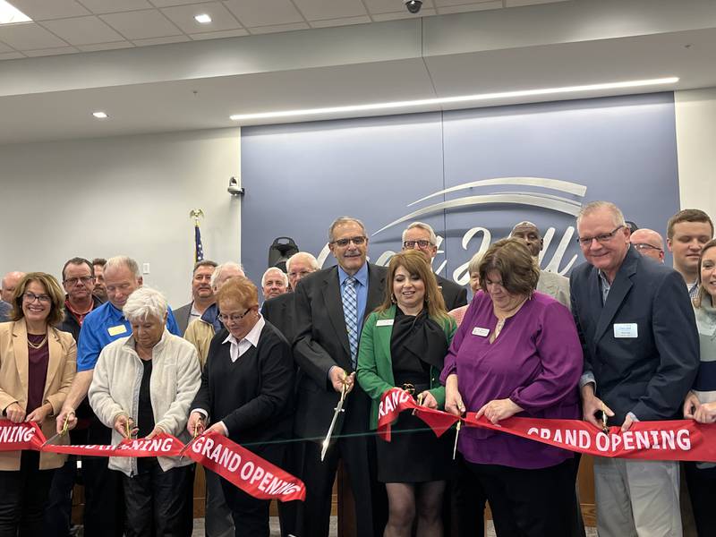 Crest Hill Mayor Ray Soliman (center) holds a pair of large scissors for a ribbon-cutting ceremony with other state and local leaders on Saturday, Oct. 21, 2023, to celebrate the Crest Hill City Center.