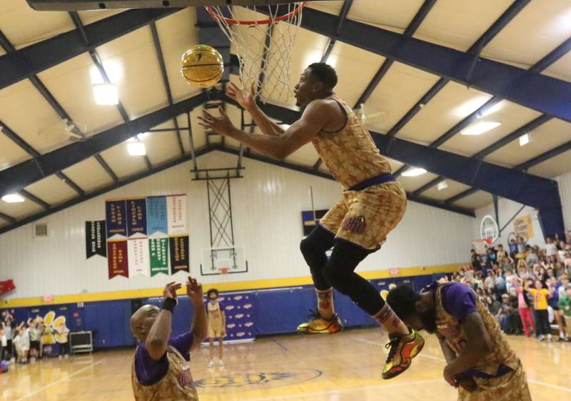 Harlem Wizards player Devon Curry (Livewire) leaps over players to score on a dunk during the Harlem Wizards event on Tuesday, Oct. 28, 2025 in Pannebaker Gymnasium at Logan Jr. High School in Princeton. Curry, toured with the Harlem Globetrotters and And1and was the NIKE Slam-Dunk Champion.