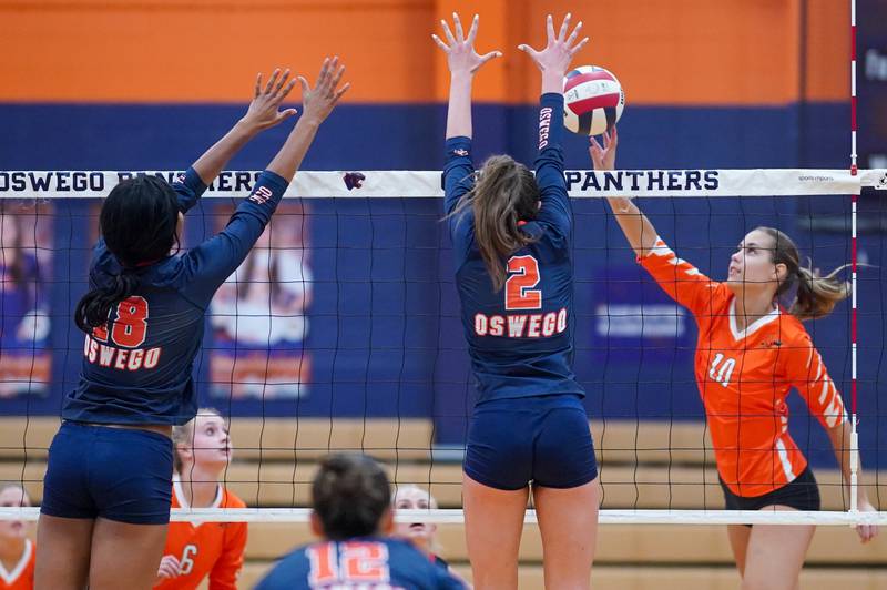 Minooka’s Courtney Walter (10) plays the ball at the net against Oswego’s Maya Norlin (18) and Kelsey Foster (2) during a volleyball match at Oswego High School on Thursday, Oct. 3, 2024.