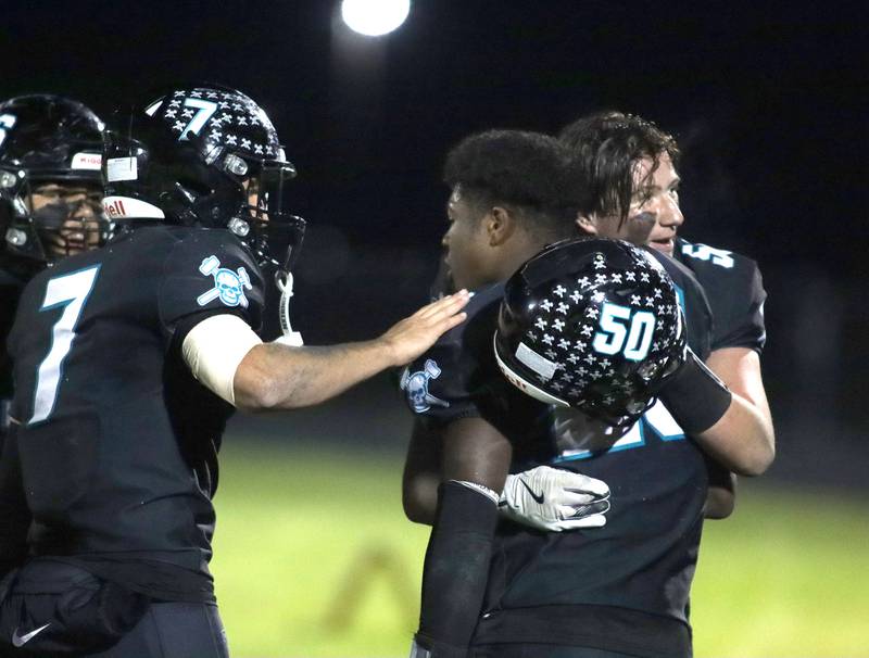 Woodstock North’s Parker Halihan, left, and Landon Rice, right, congratulate David Randecker, center, after Randecker eclipsed the all-time program rushing record against Woodstock in varsity football at Woodstock North High School on Friday, October 24, 2025.