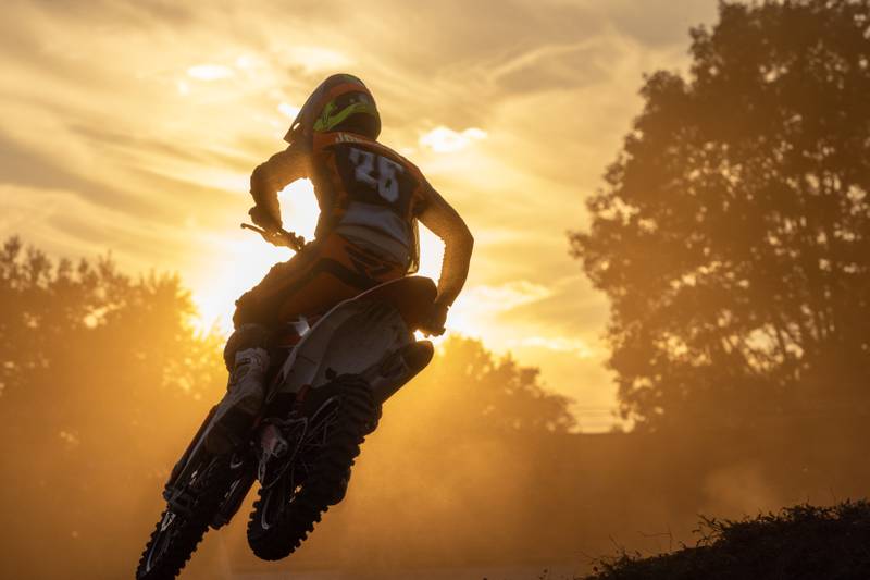 Dust fills the air as a motocross racer jumps into the sunset during Megacross at the Tri County Fair on August 30, 2025 in Mendota.