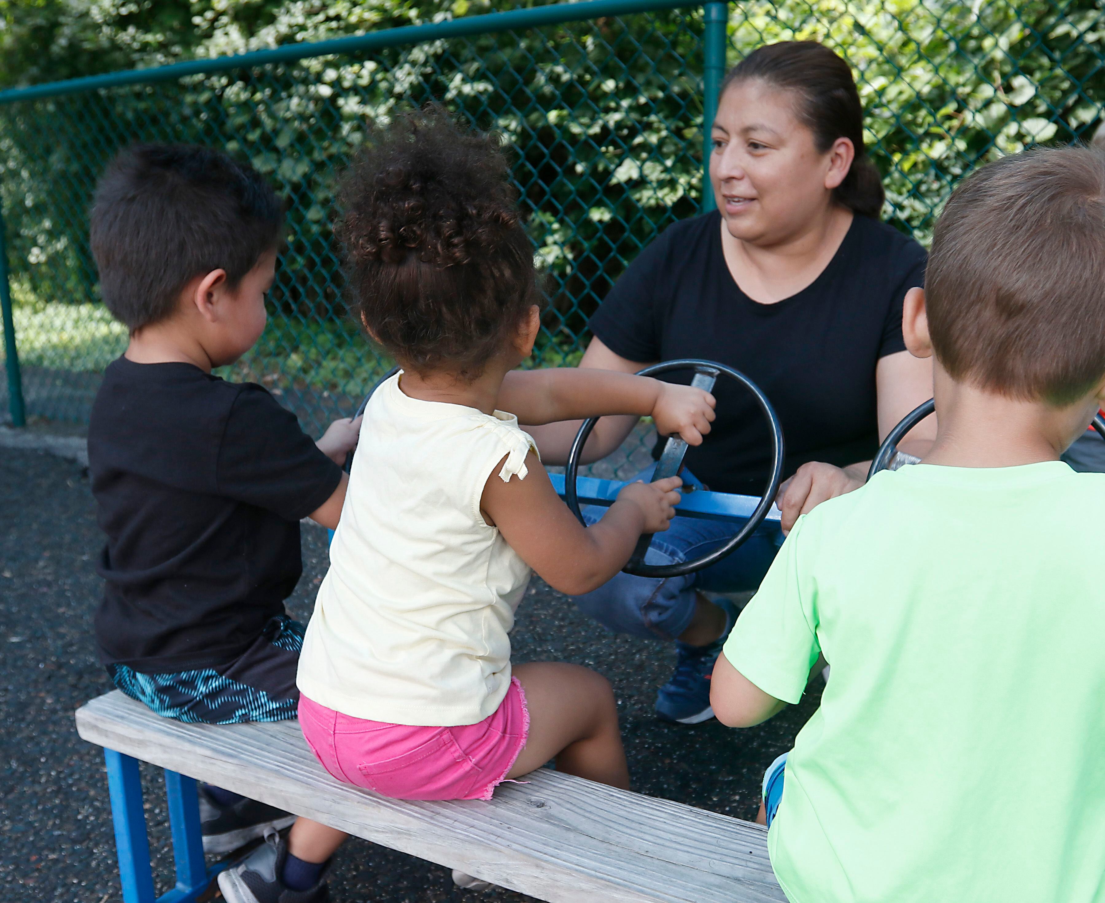 Teacher Nunez Arias interacts with a with children as they play on the playground Thursday, July 28, 2022, at the Friendship House, 100 South Main Street, in Crystal Lake. Childcare centers are struggling to find enough teachers to maintain operations.