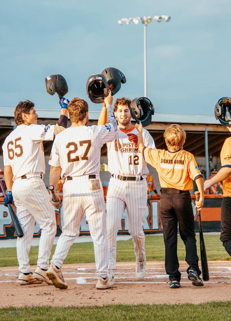 Pistol Shrimp teammates meet Ryan Niedzweidz at home plate to celebrate one of two home runs for the Illinois Valley leadoff man Saturday, Aug. 4, 2024, in Peru.
