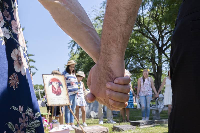 The family joins hands and says a prayer Friday, July 7, 2023 at the end of the graveside ceremony.