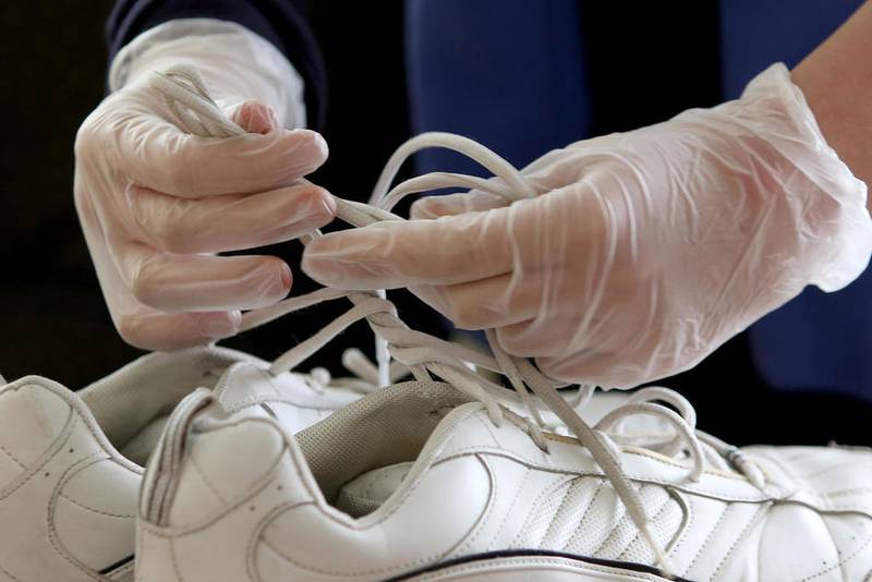 A volunteer ties a pair of donated sneakers together to gather for a fundraiser.