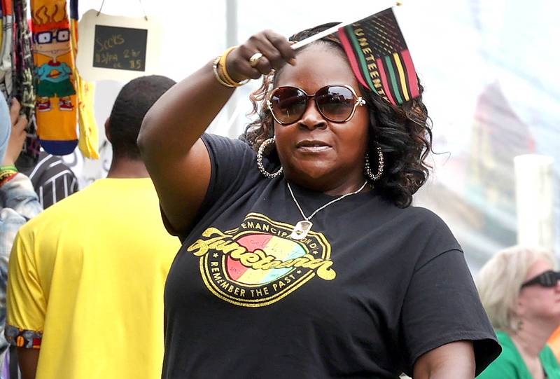 Lucretia Konan, associate vice president of college relations at Kishwaukee College, waves her Juneteenth flag during the Juneteenth Community Celebration Saturday, June 15, 2024, at Hopkins Park in DeKalb.