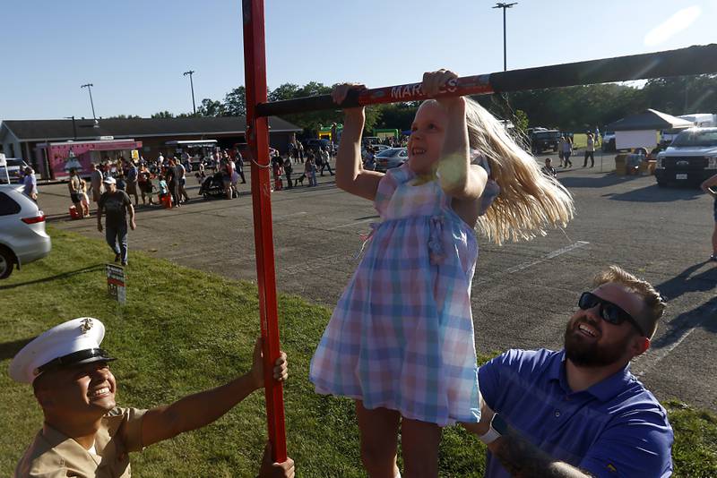 U.S.Marine Corps Lance Cpl. Filiberto Garcia watches as Harper Mackenzie, 6, of McHenry,does pull-ups as she is spotted by her dad, Will, during National Night Out! Tuesday, August 9, 2022, at Petersen Park in McHenry. The event was put on by the McHenry County Sheriff’s Office, City of McHenry Police Department and the McHenry County Conservation District and featured demonstrations, food and fun activities. National Night Out is held nationally in over 50,000 cities and is designed to help create relationships between neighbors and law enforcement community.