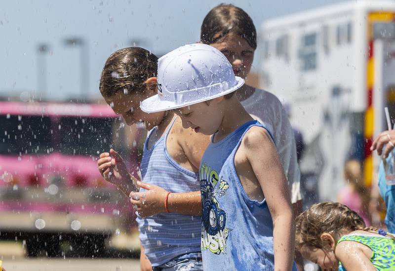 Declan Dickey, 10, lets the cooling water run off his hat Saturday, June 28, 2025, at Rock Falls' Touch-a-Truck event. The fire department set up the cooling shower for the people to beat the heat.