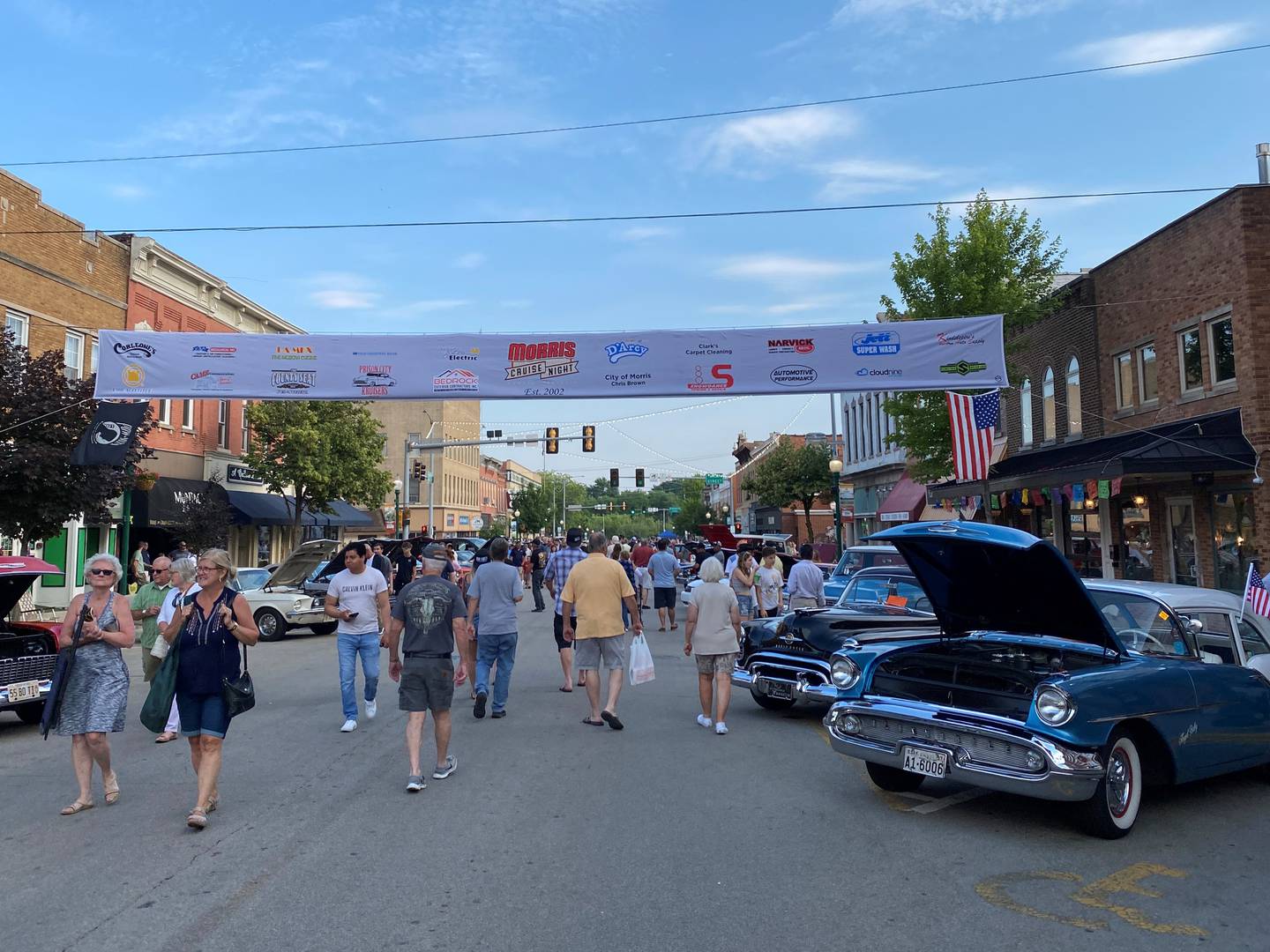 A crowd of people looks at the cars as they wander down Liberty Street during Morris Cruise Night.