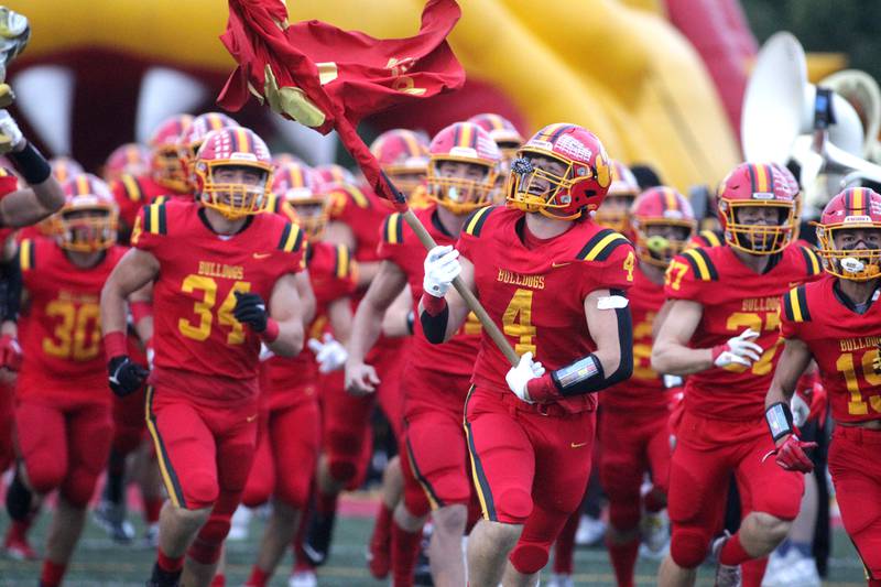 Batavia’s Charlie Whelpley carries the flag onto the field before their home game against Wheaton North on Friday, Sept. 22, 2023.