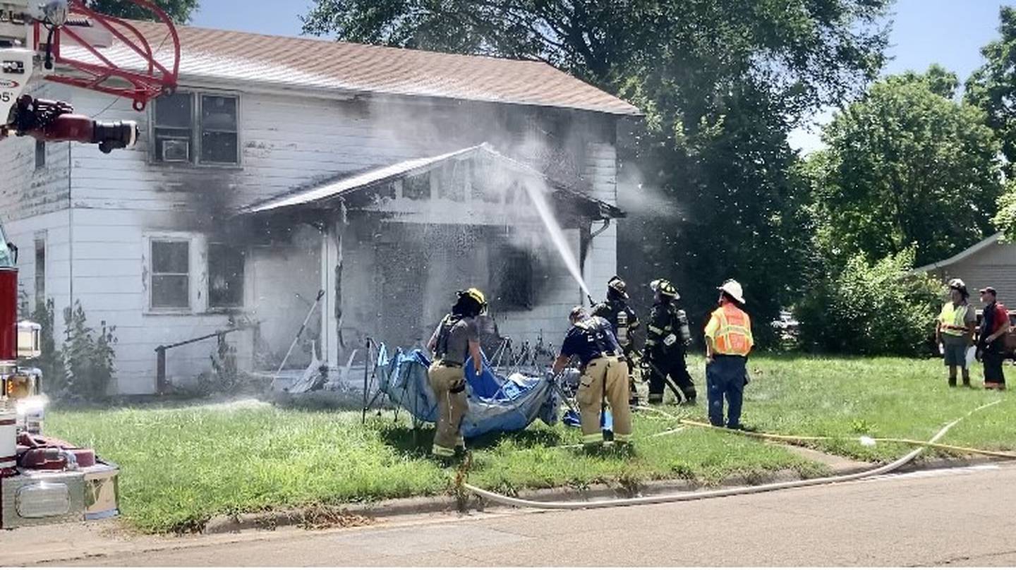 Area fire fighters put out a hot spot on the porch roof of a residential fire of the 200 block of West Clark St. in Princeton on Friday afternoon. Neighbors brought bottled water to help the fire fighters to combat the 100-degree plus heat index.