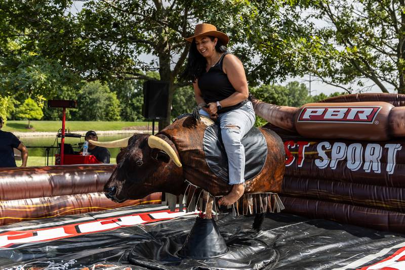 Wisconsin resident Minerva Sanchez rides a mechanical bull at Barro Fest at Settlers' Park in Plainfield on July 27, 2024.