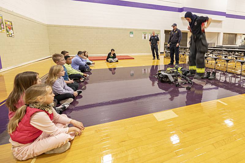 Dixon City firefighter Tyler Hansler pulls on his gear Thursday, Oct. 12, 2023 during a demonstration for Fire Prevention Week at Jefferson School.