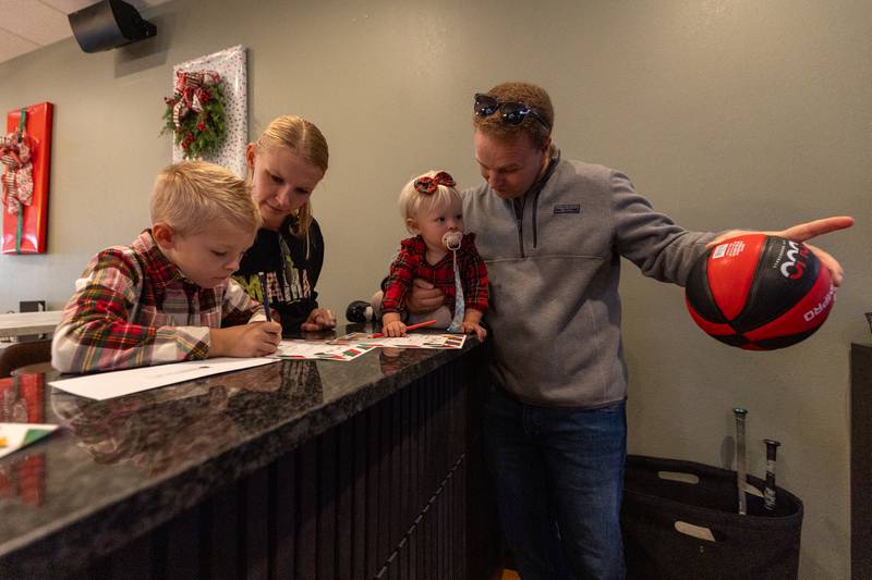(from left) Brooks Ebener writes letter to Santa with the assistance of his mother Nichole as Evelyn and Andrew look at Elf at the annual Christmas in the Valley on Saturday, November 15, 2025 at the Tee Box in Spring Valley.