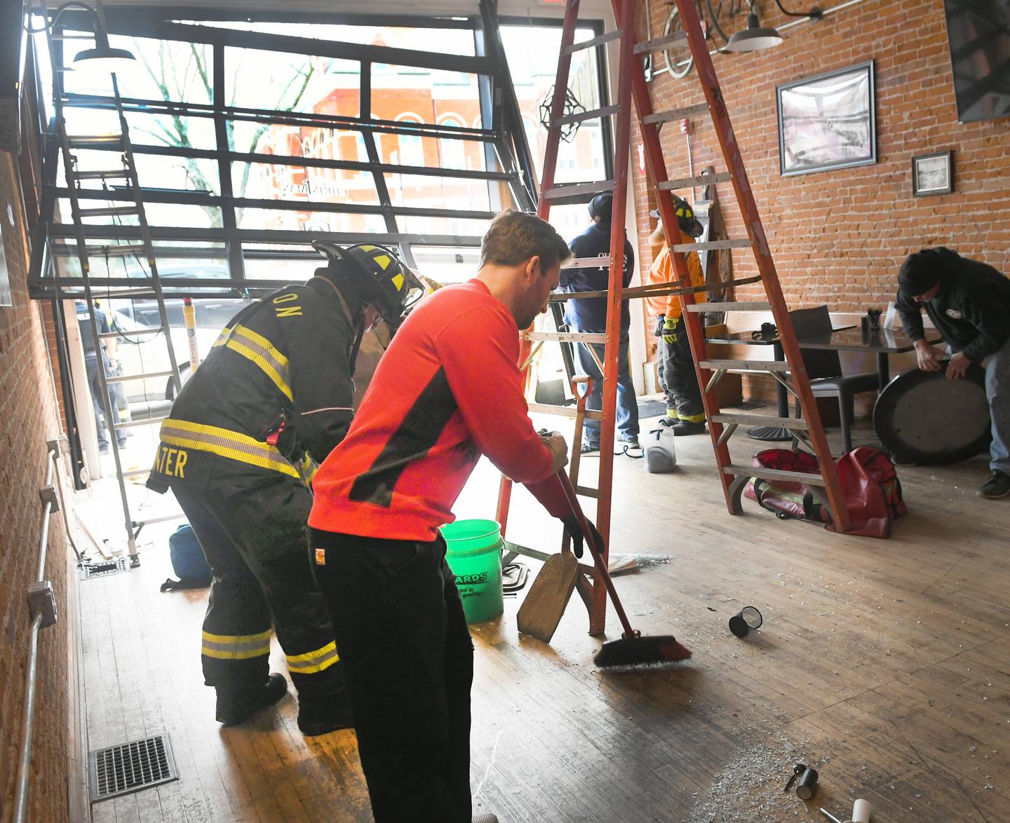Dan Gale, of Oregon, and firefighter sweep up broken glass after a vehicle crashed into the Ogle County Brewery in downtown Oregon early Sunday afternoon after being struck by another vehicle at the intersection of Illinois 64 and Illinois 2. Dan's father, Mark, is one of the owners of the building.