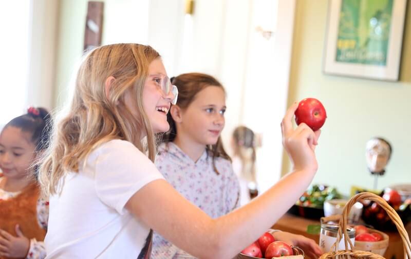 Maycee Hale, 9, of St. Charles gets a closer look at one of the apples she picked for a recipe during a Fun Friday with The Learning Door at the Farmhouse School in Campton Hills.