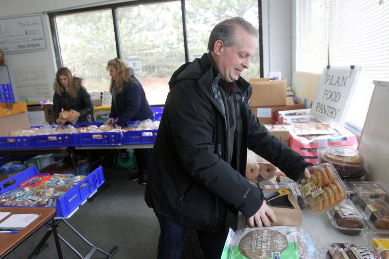 Pastor Mike Pimpo, director & founder, (on right) arranges baked goods on a table for patrons while working with Adriana Garcia, of Chicago and Chryssy Alba at the P.L.A.N. Food Pantry in Round Lake Beach.