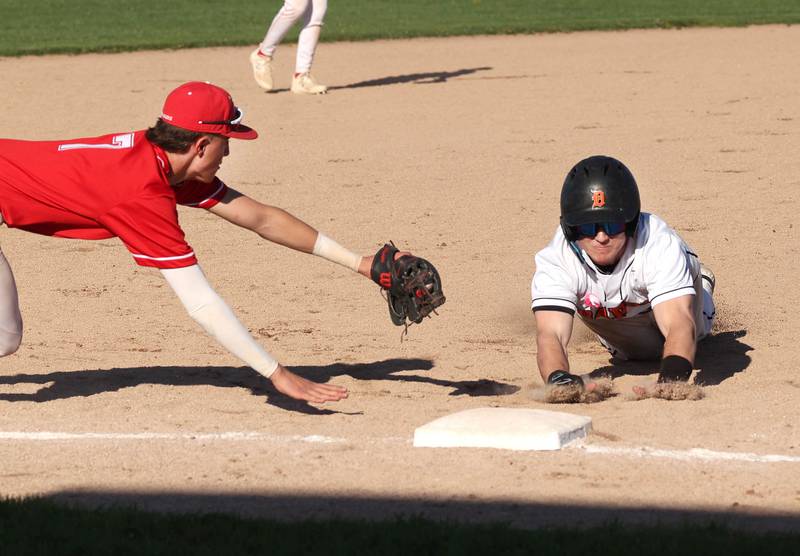 DeKalb's Matthew Clayton is out diving into third base as Naperville Central's Henry Paul dives to make the tag just in time during their game Tuesday, April 30, 2024, at DeKalb High School.