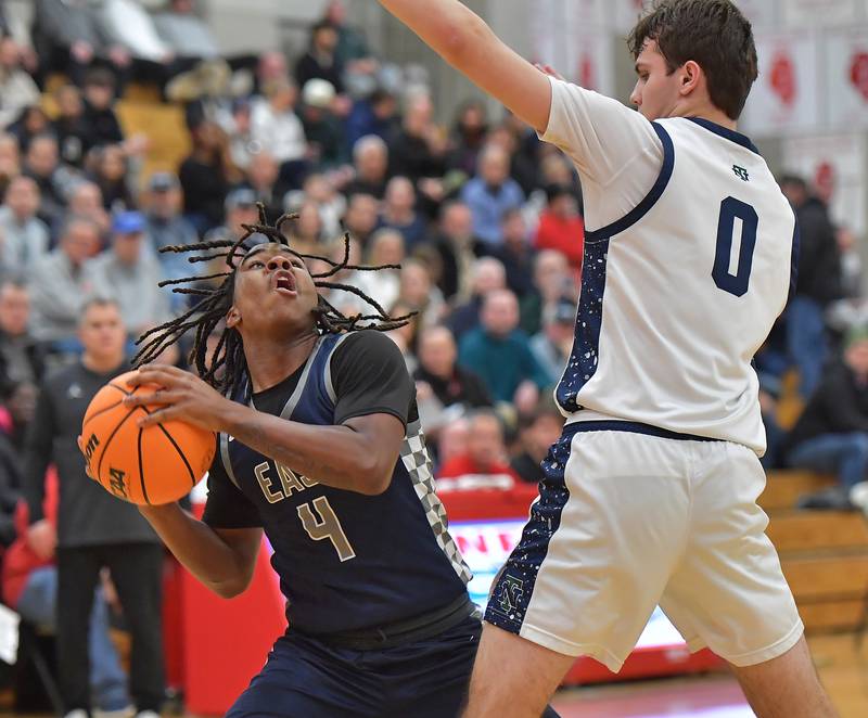 Oswego East’s R'mani Sims (4) looks to shoot as New Trier’s Owen Foster (0) defends during a When Sides Collide Shootout game on January 24, 2026 at Benet Academy in Lisle.