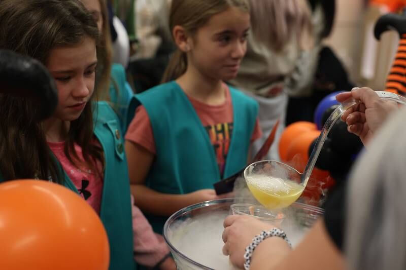 Emiliya, left, from Plainfield waits for her drink from the fog filled Hocus Pocus Punch bowl at the STEAM Spooktacular hosted by the After the Peanut Foundation on Wednesday at Lewis University.
