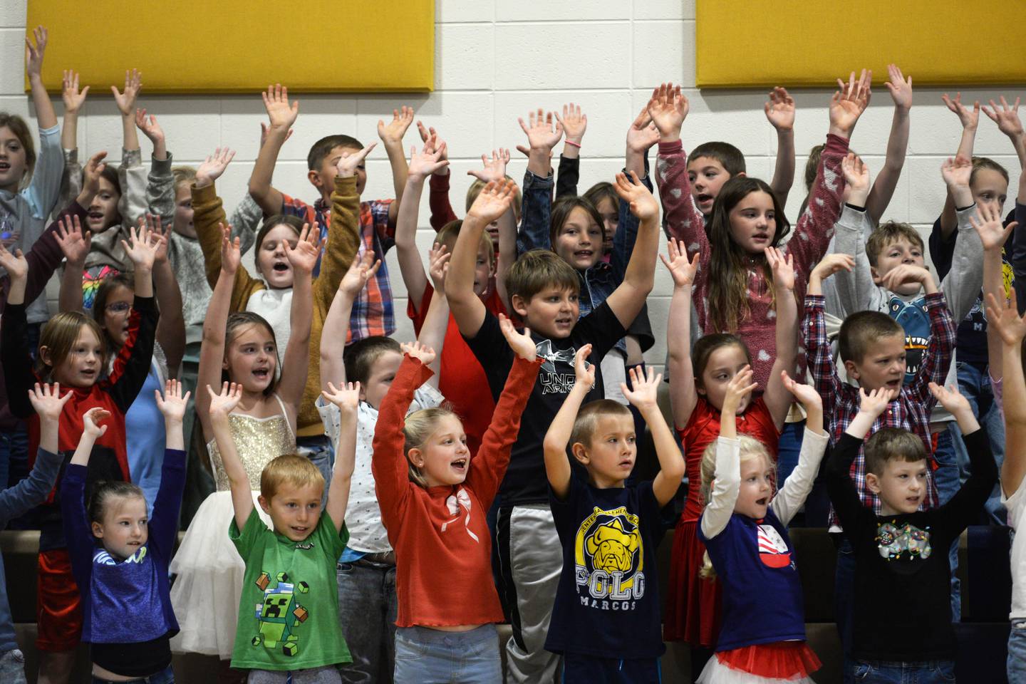 Centennial Grade School students wave their arms in the air as they sing a patriotic song at the Veterans Day ceremony in Polo on Monday, Nov. 11, 2024.