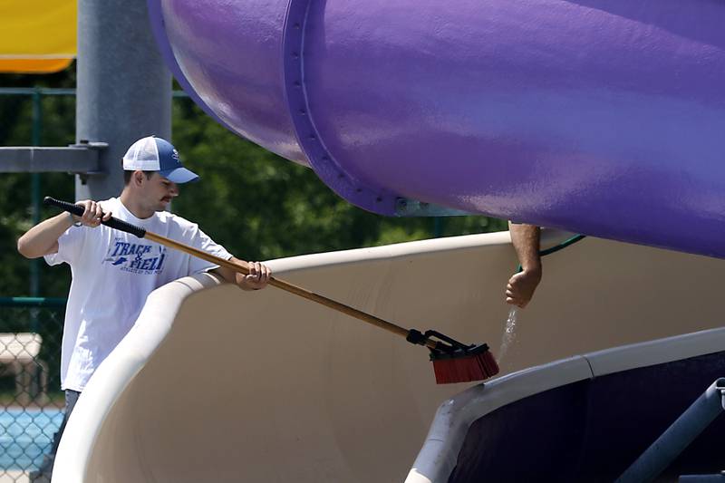 Lifeguard Jared Kniola cleans a slide Wednesday, May 24, 2023, at the Woodstock Water Works Aquatics Center in Woodstock as the pool gets ready to open on Saturday.