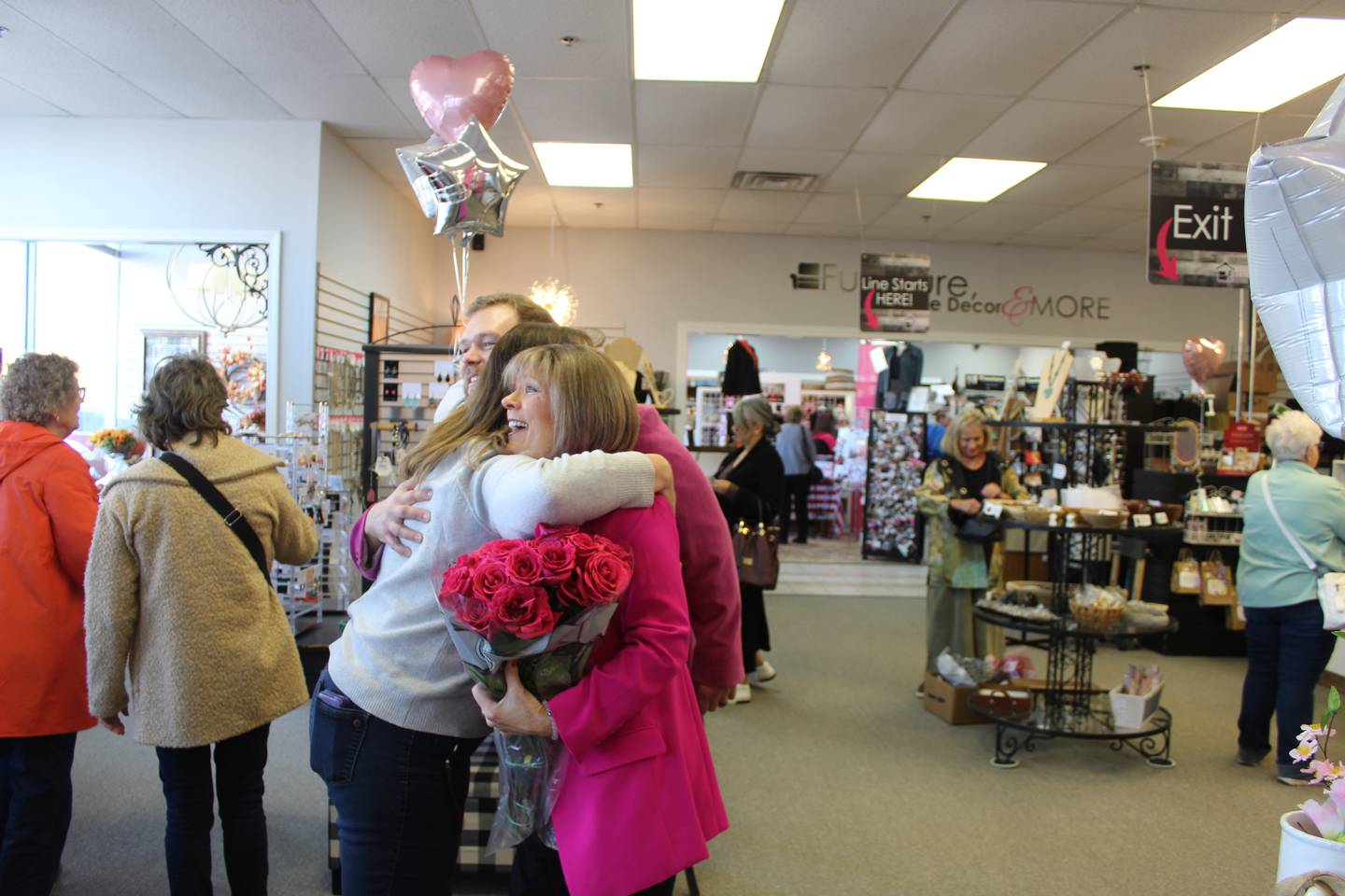 Best Friend's Consignment owner Marianne Evans hugs a customer who brought her flowers for the store's 20th anniversary.
