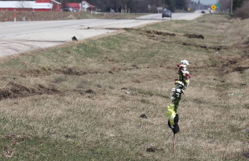 Ruts in the grass and skid marks can be seen near a memorial Friday, March 29, 2024, at the site on Route 23 three-quarters of a mile south Perry Road, near DeKalb where a DeKalb County Sheriff’s deputy was killed in a crash early Friday morning.