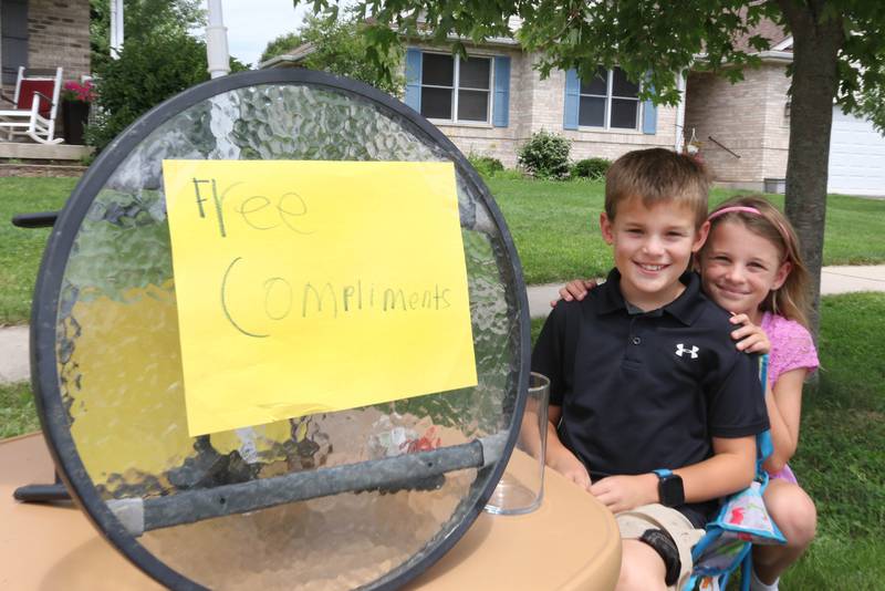 Ethan Wargo, 9, and his twin sister, Claire, at the free compliments stand in front of their house Thursday, July 24, 2025, in Sycamore. Ethan offers free compliments to anyone who stops by, but he said tips are accepted and appreciated.
