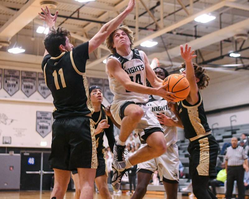 Kaneland's Luke Reinert, center, goes up for a shot during the game on Wednesday Dec. 11, 2024, while being defended by Sycamore's Jakob Shipley (11) and Josiah Mitchell (1) held at Kaneland High School in Maple Park.