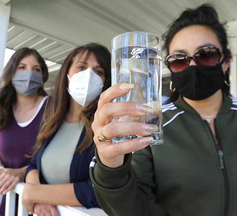 Citizens for Clean Water Sycamore members Alyssa Force (from left), Amber Quitno, and Jessica Pennington inspect a glass of water Oct. 7 at a house on Edward Street in Sycamore.