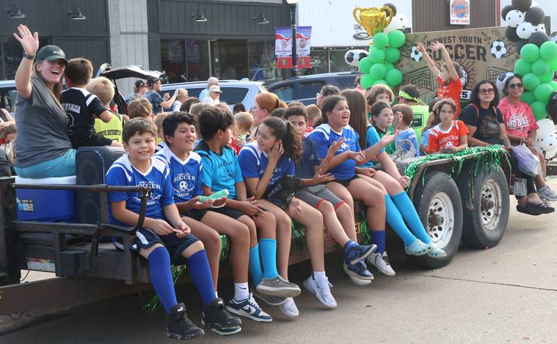 Kids with the Midwest Youth Soccer League ride on a float during the Homecoming parade on Thursday, Sept. 18, 2025 downtown Spring Valley.
