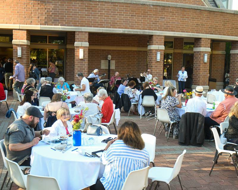Community members enjoy some serene seasonal weather and outdoor music as they taste test their way through various dishes during the 20th anniversary of 50 Men Who Cook, an annual fundraiser hosted by CASA DeKalb County at the Barsema Alumni and Visitors Center at Northern Illinois University in DeKalb on Saturday, Aug. 10, 2024.