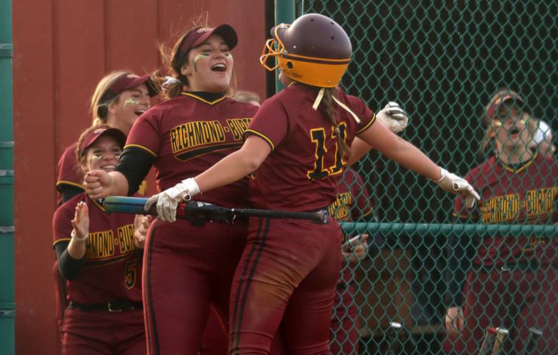Richmond-Burton’s Sydney Hird, right, celebrates with  Norah Spittler, center, at the dugout after Hird scored the go-ahead run in an extra-inning win in varsity softball at Marengo Wednesday evening.