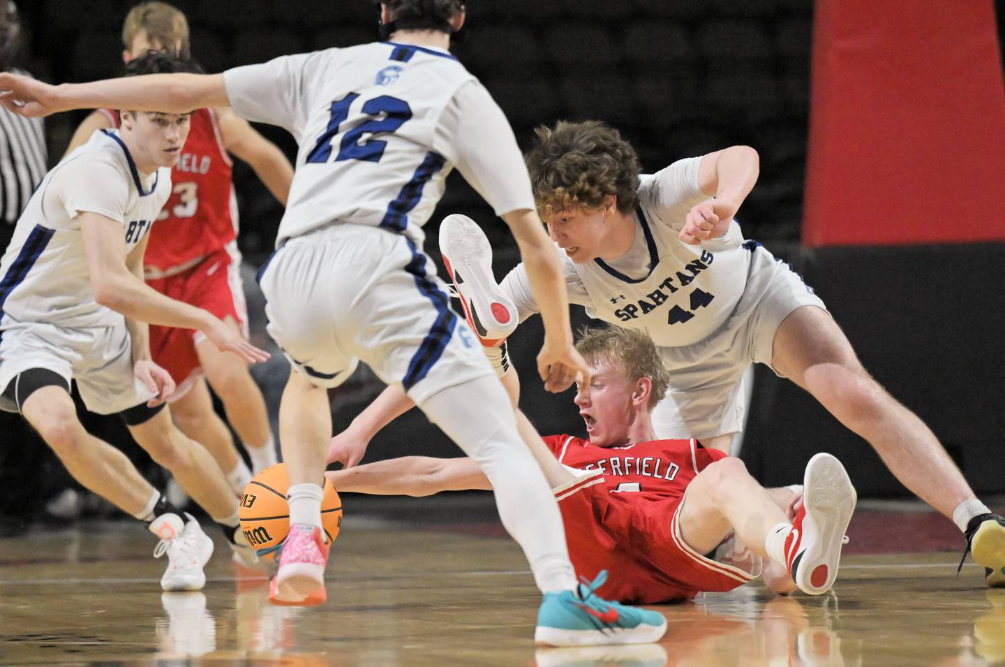 Deerfield’s Tommy Donahue stretches for the ball as St. Francis’ Nathan Silagi, left, Benjamin Whorlow and Tanner Hozian, foreground, surround him in the IHSA Class 3A supersectional championship game at the Now Arena in Hoffman Estates on Monday, Mar. 9 2026.
