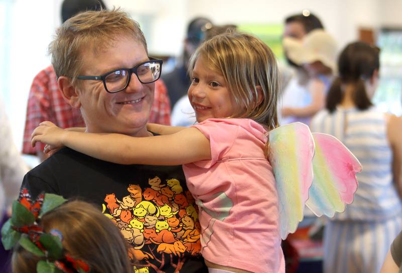 Andrew Pickett of Lake in the Hills waits with his daughter Raelyn, 5, for face painting during Monarchs and Music at Crystal Lake Main Beach Sunday.