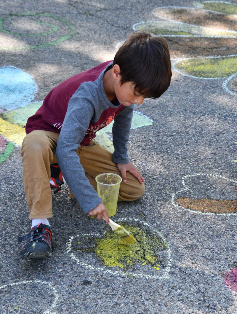 Aleksander Martinkus colors a drawing in with sidewalk chalk Saturday, May 27, 2023, during Sidewalk Chalkapalooza at Soldiers and Sailors Park in Princeton.