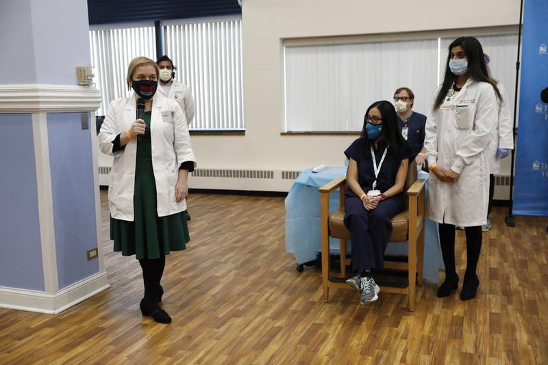 Dr. Allison Arwady, left, commissioner of the Chicago Department of Public Health, speaks near Dr. Marina Del Rios, seated, from University of Illinois Hospital & Health Sciences System, who received Chicago's first COVID-19 vaccination from Dr. Nikhila Juvvadi, right, on Tuesday, Dec. 15, 2020, at Loretto Hospital, a 122-bed medical facility in the Austin neighborhood of Chicago. (Jose M. Osorio/Chicago Tribune via AP)