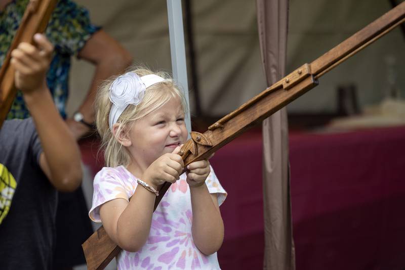 Claire Albrecht, 6, of Ohio, checks out a replica wooden rifle Saturday, Sept. 21, 2024, an educational booth at Fall and Fantasy Fest.