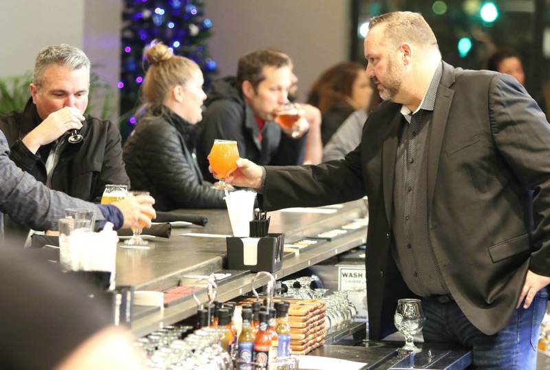Scott Struchen, one of the founders and chief commercial officer of Keg & Kernel by Tangled Roots Brewing Company, serves a beer Wednesday, Dec. 8, 2021, after a ribbon cutting at the restaurant at 106 East Lincoln Highway in DeKalb. The official opening will be Saturday Dec. 11