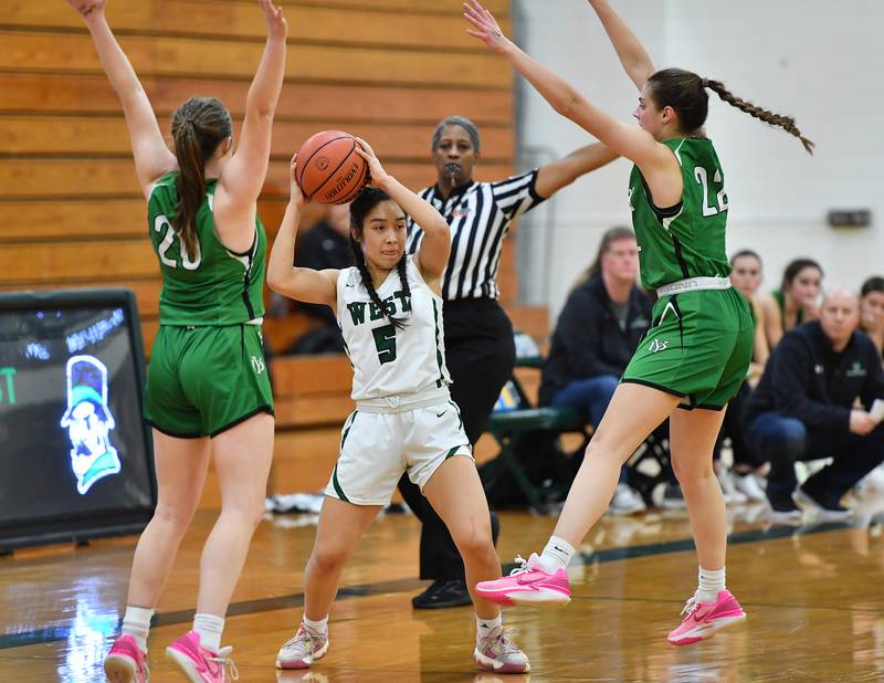 Glenbard West's Lauren Escalante (5) starts to pass as she is double teamed by York's Hannah Meyers and Stella Kohl (22) during a game on Jan. 22, 2024 at Glenbard West High School in Glen Ellyn.