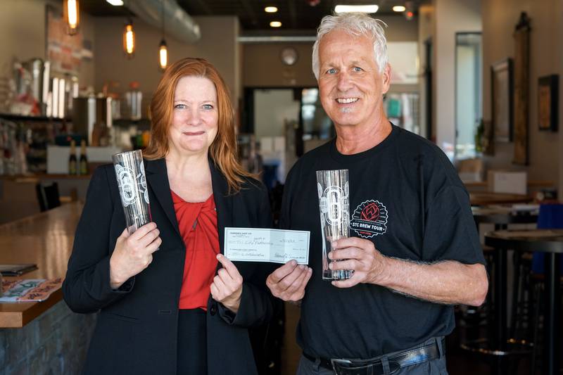 Tri City Health Partnership Executive Director Kim Lamansky, left, stands next to Ed Seaman, right, the owner of Broken Brix Homebrew Shop in St. Charles, one of the six breweries that collaborated together to create a beer. A portion of the sales went to Tri City Health Partnership.