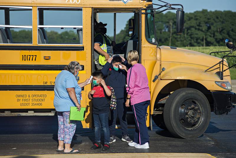 Students have their temperature read as they file off the bus at East Coloma-Nelson School August 12, 2020. After the temperature is read students use one of three entrances to enter the building depending on class level.
